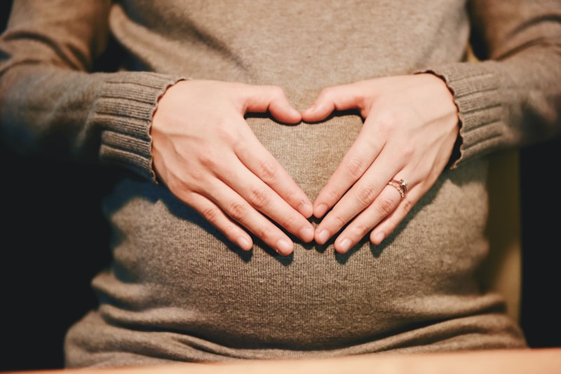 Schwangere Frau haelt ihren Bauch